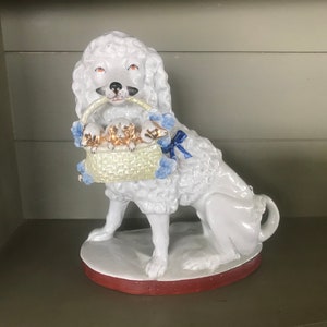 Large porcelain English poodle carrying a basket.