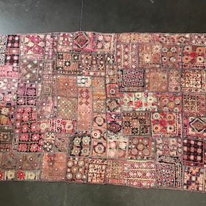 May include: A patchwork rug featuring a mix of pink, red, and brown fabrics. The rug is crafted from various pieces of fabric stitched together, creating a distinctive and eclectic design.