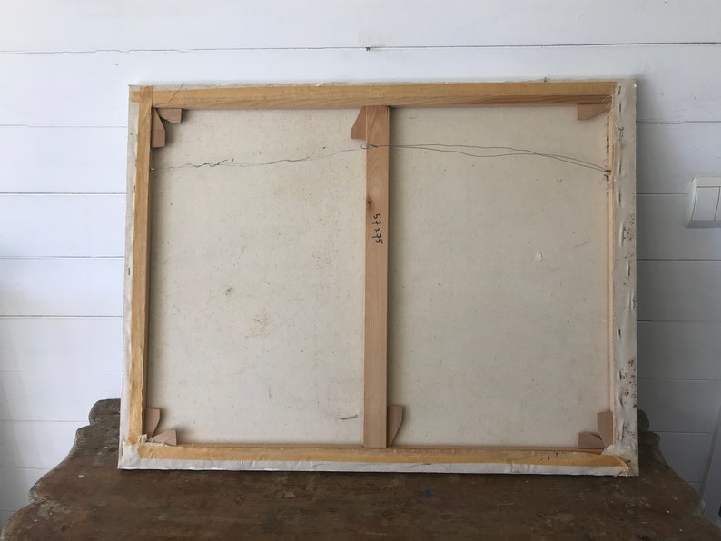 Op de afbeelding: De achterkant van een gespannen canvas schilderij met een houten lijst. Het canvas is wit en de lijst is van natuurlijk hout. De achterkant van de lijst heeft een houten steun met het nummer "52x45" erop.