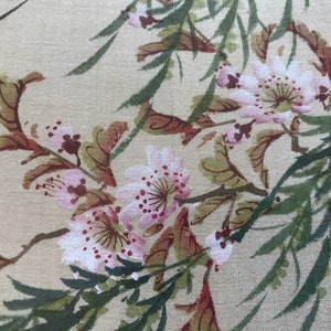 May include: A beige fabric with a floral pattern of pink flowers and green leaves. The flowers have a watercolor effect with pink petals and red centers.