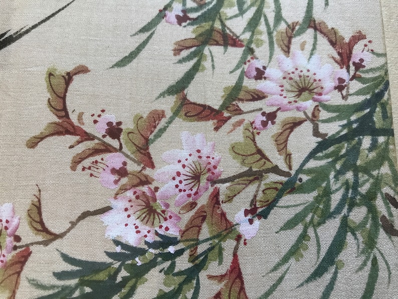 May include: A beige fabric with a floral pattern of pink flowers and green leaves. The flowers have a watercolor effect with pink petals and red centers.