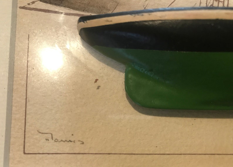 May include: Close-up of a green, black and white model ship hull. The ship is painted with a green bottom, black midsection and white top. The ship is signed "Tommis".