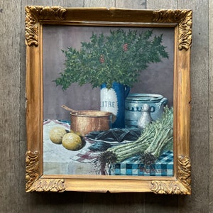 Puede incluir: Una pintura de bodegón en un marco dorado que representa una jarra de cerámica azul y blanca, una olla de cobre, un cuenco de mejillones, limones y un manojo de tallos verdes sobre un mantel a cuadros. La pintura está firmada "Bruykenier".