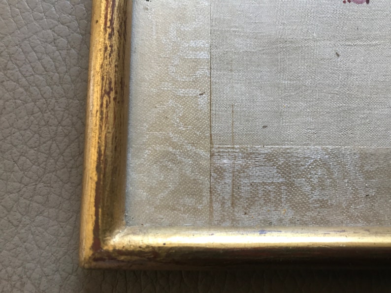 May include: Close-up of a gold-colored frame with a textured surface. The frame is made of wood and has a slightly distressed look.
