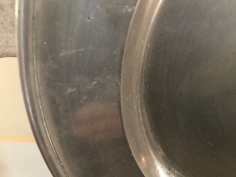 May include: Close-up of a silver metal serving tray with a smooth, slightly worn surface.