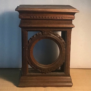 Peut inclure: Un piédestal en bois brun foncé avec une base carrée et une ouverture circulaire au centre. Le piédestal est orné de sculptures complexes autour de l'ouverture et sur le dessus.