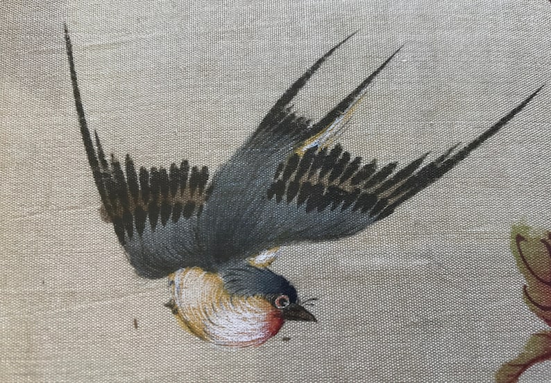 May include: A painted image of a brown and gray bird with black wings flying in mid-air. The bird is painted on a beige linen background.