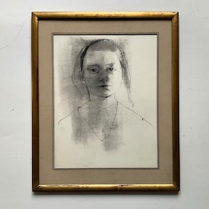 May include: A framed black and white pencil drawing of a person's face. The person has short hair and is wearing a collared shirt.