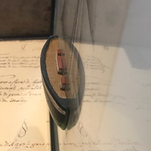 May include: A small, wooden model ship with red and white sails. The ship is displayed in a glass case.