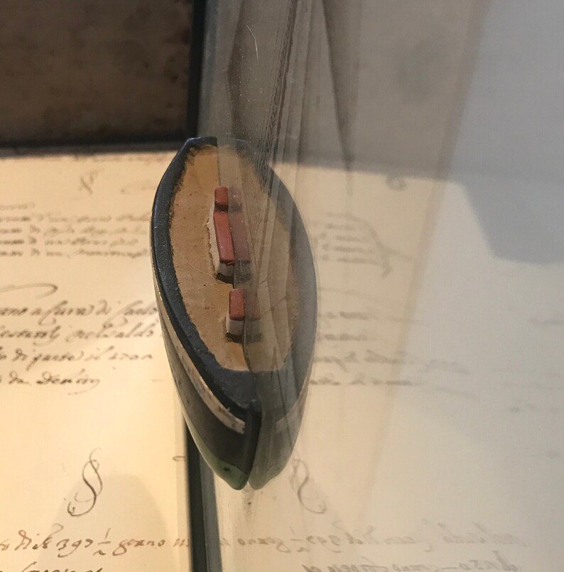 May include: A small, wooden model ship with red and white sails. The ship is displayed in a glass case.