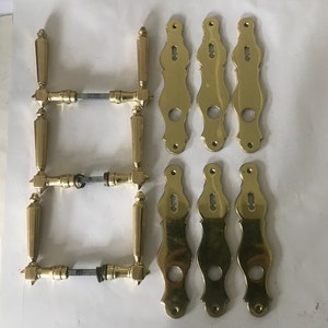 Peut inclure: Ensemble de huit poignées de porte en laiton, comprenant six plaques décoratives et deux ensembles de poignées de porte avec un trou de serrure. Les poignées sont toutes de style traditionnel avec une finition polie.
