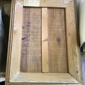 Op de afbeelding: De achterkant van een houten fotolijst met een label waarop "El Americano" en "Made in Mexico" staat.