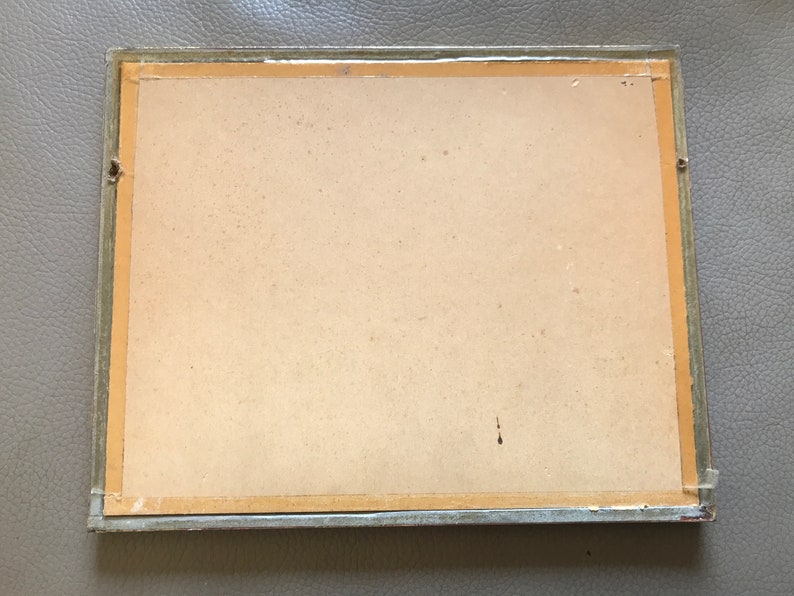 May include: A plain, off-white picture frame with a light brown mat and a silver-colored frame. The frame is slightly damaged on the top left corner.