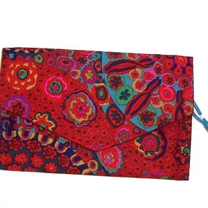 May include: A rectangular fabric wallet featuring a vibrant, multicolored floral and abstract pattern dominated by shades of red, blue, and orange. The wallet has a triangular flap closure and a small, light blue fabric pull tab on the side.