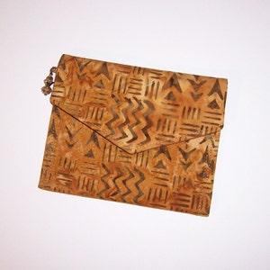 May include: A brown and tan fabric clutch with a geometric pattern. The clutch has a flap closure and a metal chain strap.