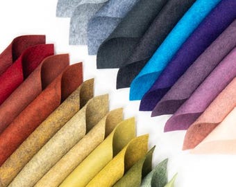 Puede incluir: Una variedad de muestras de tela de fieltro en diferentes colores, incluyendo rojo, naranja, amarillo, verde, azul, morado, rosa y gris. Las muestras están dispuestas en un patrón de arcoíris.