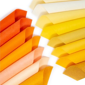 May include: A collection of felt sheets in various shades of orange and yellow, arranged in a gradient pattern. The sheets are folded and stacked, creating a visual display of color.