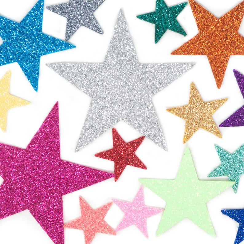 May include: A selection of glittery star decorations in a range of colours, including silver, blue, pink, orange, and green. The stars are arranged on a white background, creating a festive display. These decorative stars are ideal for crafts and celebrations.