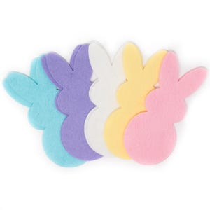 May include: A collection of colorful felt bunny shapes in pastel shades of blue, purple, white, yellow, and pink. These Easter-themed decorations are arranged in a row, perfect for crafts and spring decor.