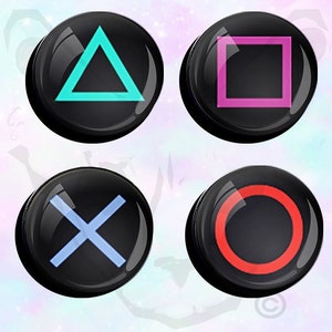 May include: Four black round buttons with different colored symbols. The symbols are a turquoise triangle, a pink square, a light blue X, and a red circle.