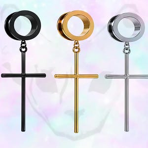 May include: Three metal cross earrings in black, gold, and silver. Each earring features a circular top connected to a dangling cross pendant. The earrings are displayed against a soft, colorful background.
