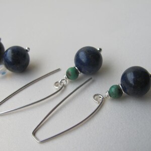 May include: A pair of silver earrings with blue and green gemstone beads. The earrings are made with a simple wire design.