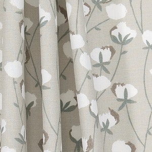 May include: A beige fabric with a white cotton flower pattern. The fabric has a subtle texture and a light, airy feel.