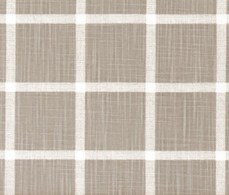 May include: A close-up view of a tan and white plaid fabric. The fabric features a textured surface with a grid pattern of thick white lines against a tan backdrop. The weave of the material is visible, enhancing its rustic appeal.