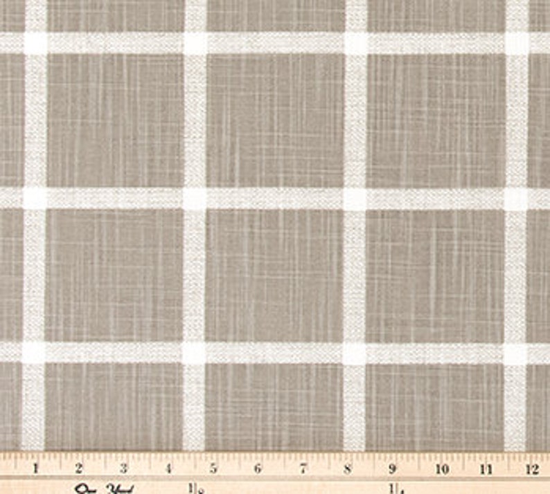 May include: Tan and white plaid fabric with a grid pattern. The fabric has a textured appearance and is measured with a ruler showing inches. The plaid design features thick white lines against a tan background.