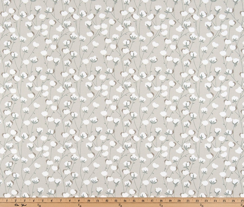 May include: A beige fabric with a repeating pattern of white cotton blossoms and green stems.