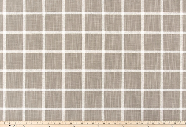 May include: Tan fabric featuring a white grid design. The fabric has a textured look, with white lines forming a grid of squares. A wooden ruler at the bottom measures up to 84 cm.