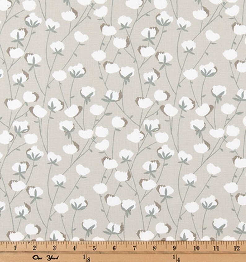 May include: A beige fabric with a repeating pattern of white cotton blossoms and green stems.