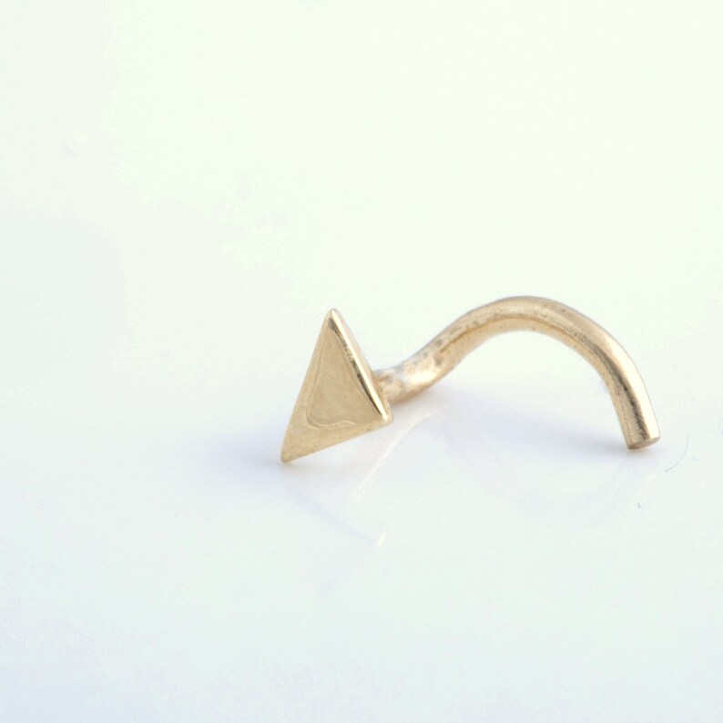May include: A gold triangle nose ring with a curved post.