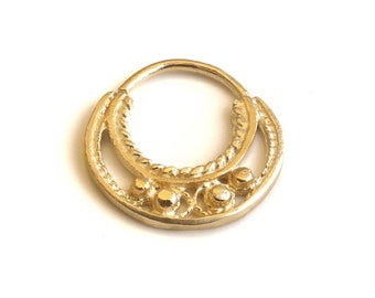 May include: Gold nose ring with a decorative design featuring a twisted rope pattern and three small beads.