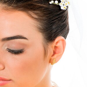 May include: A close-up of a woman's face with her eyes closed. She is wearing a small, delicate gold earring in her right ear.