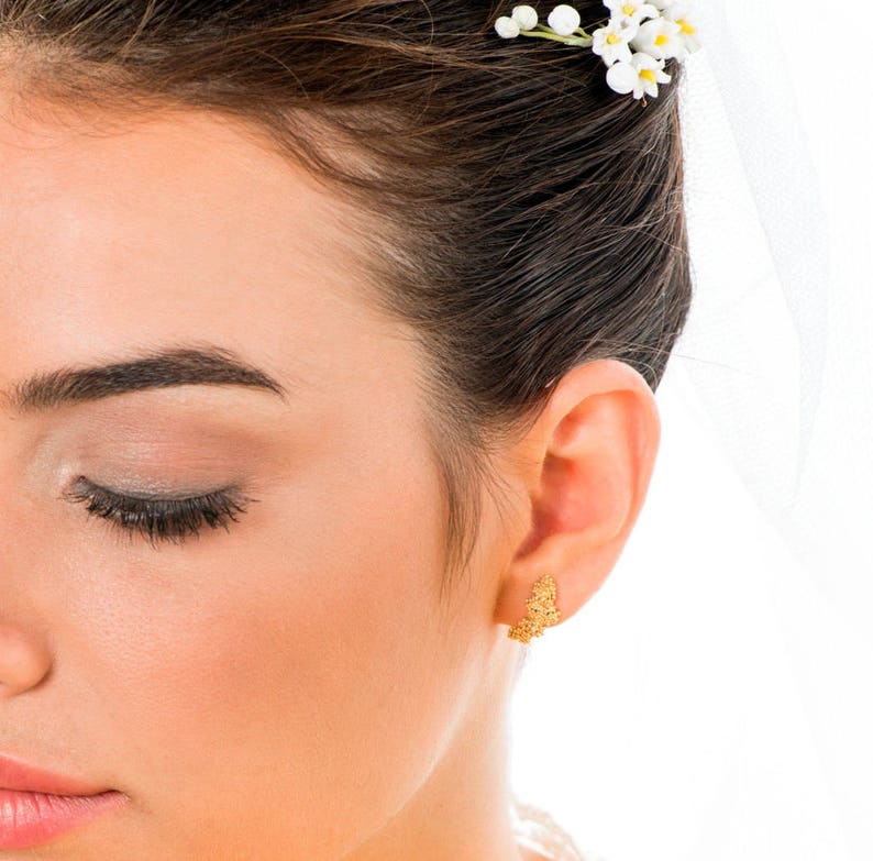 May include: A close-up of a woman's face with her eyes closed. She is wearing a small, delicate gold earring in her right ear.