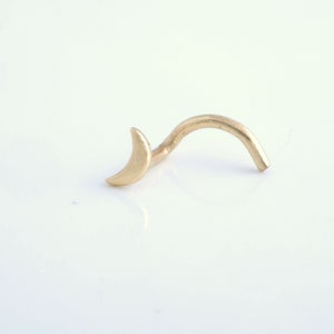 May include: A gold crescent moon nose ring with a curved post.