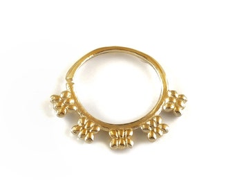 May include: Gold hoop nose ring with a decorative design of small, raised circles around the hoop. The design is repeated five times around the hoop.
