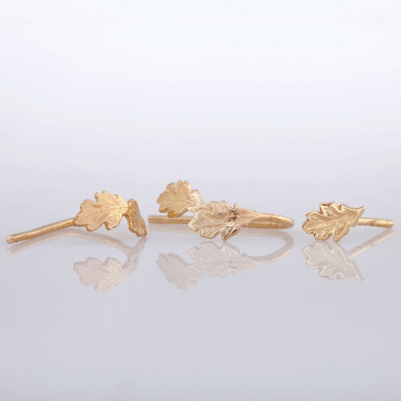 May include: Three gold leaf earrings, each featuring a different design. The first earring is a single leaf, the second earring is two leaves, and the third earring is two leaves connected by a small wire.