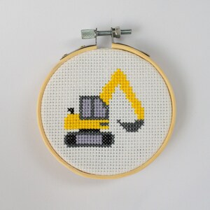 May include: A yellow and gray embroidered excavator cross-stitch design in a wooden hoop.
