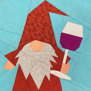 Peut inclure: Un gnome rouge et blanc avec un chapeau rouge et une barbe blanche tient un verre de vin. Le gnome est debout sur un fond bleu avec des points blancs.