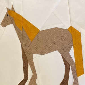 May include: A brown and yellow geometric horse quilt block. The horse is made of fabric pieces sewn together to create a patchwork design.