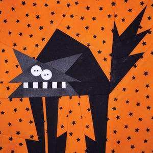 May include: Black cat applique with white teeth and two white eyes on an orange background with black stars.