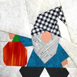 May include: A patchwork quilt block depicting a gnome holding a pumpkin. The gnome is wearing a black and white checked hat, a blue and white striped shirt, and blue trousers. The pumpkin is orange with red and yellow stripes.