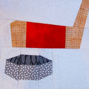 May include: A red and brown fabric applique of a hockey stick and puck. The puck is grey with white polka dots.