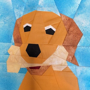 May include: A brown and white patchwork fabric dog with a brown nose and black eyes. The dog is holding a bone in its mouth.