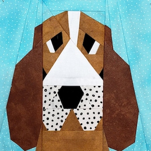 May include: A brown and white patchwork quilt block featuring a stylized image of a dog's face. The dog has brown ears, a white nose, and black eyes. The quilt block is made up of various geometric shapes.