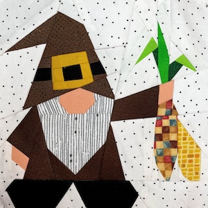 Peut inclure: Un gnome en patchwork marron et blanc tenant un épi de maïs vert et jaune. Le gnome porte un chapeau marron avec une bande jaune et une chemise rayée.