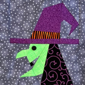 Puede incluir: Una bruja verde con un sombrero morado y remolinos negros y morados en su vestido. La bruja está sobre un fondo de estrellas blancas sobre una tela gris.