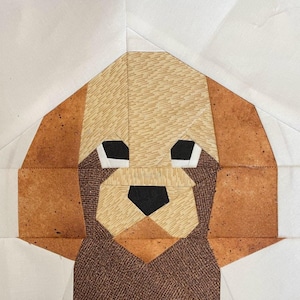May include: A brown and tan patchwork fabric dog with black eyes and nose. The dog is made of different fabric patterns and is a geometric design.